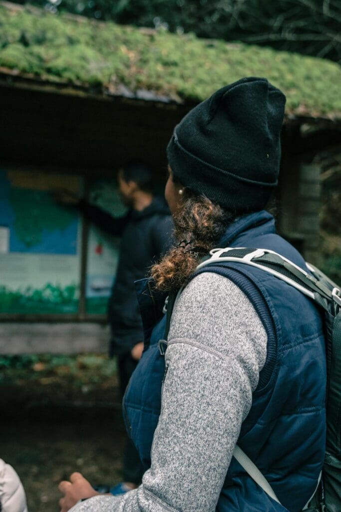 Outdoor wellness guide with backpack reading a trail sign during a group hike
