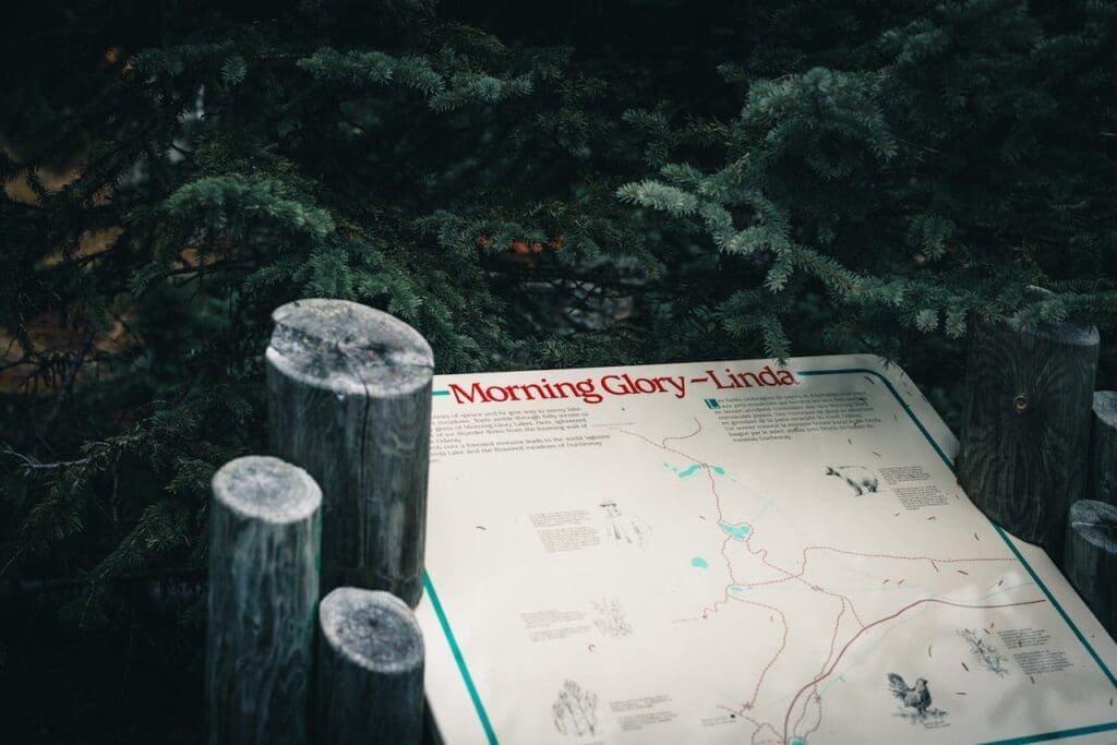 A detailed trail map sign surrounded by evergreen trees at an outdoor wellness retreat location.